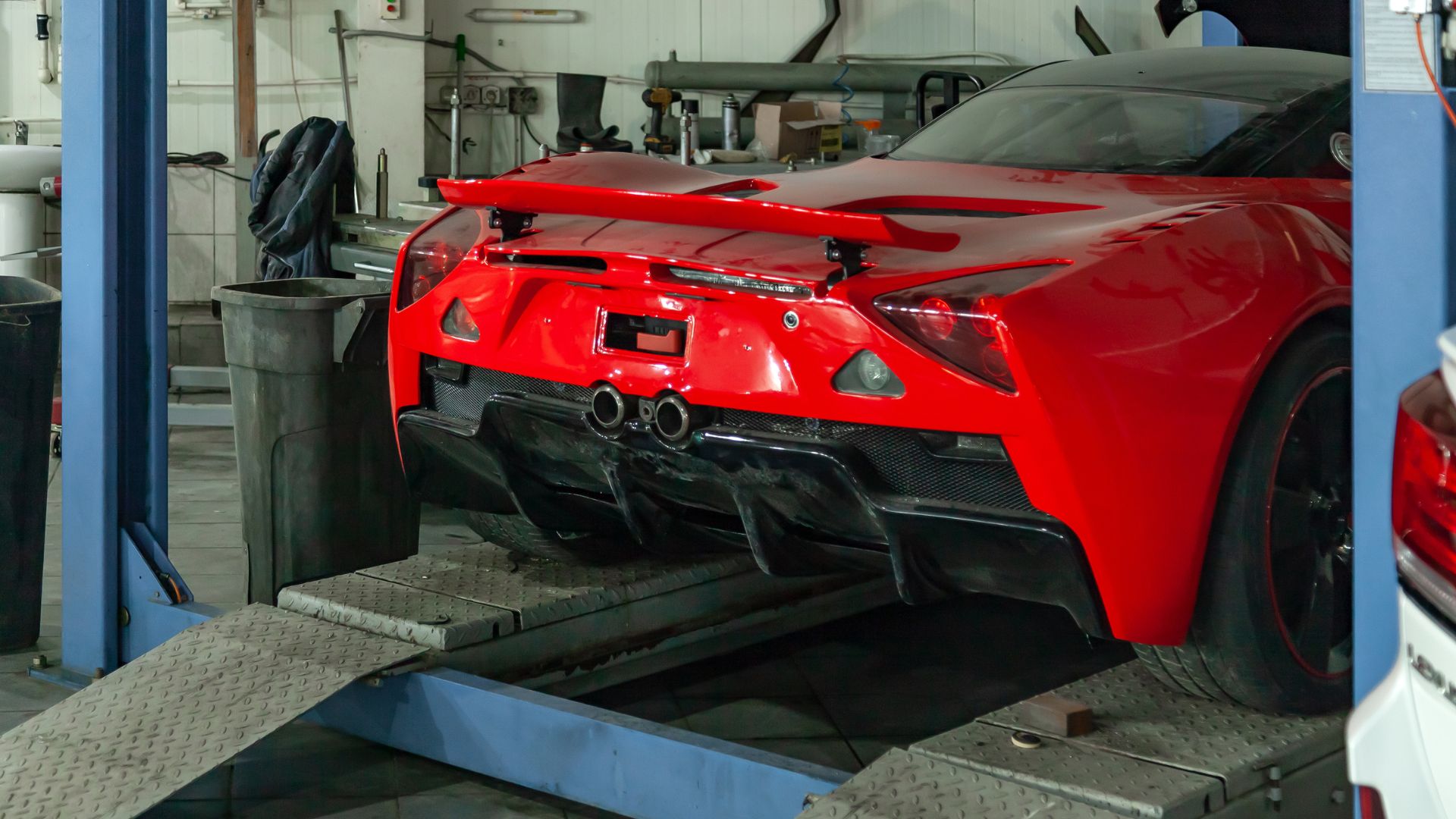 A red sports car being worked on in a garage