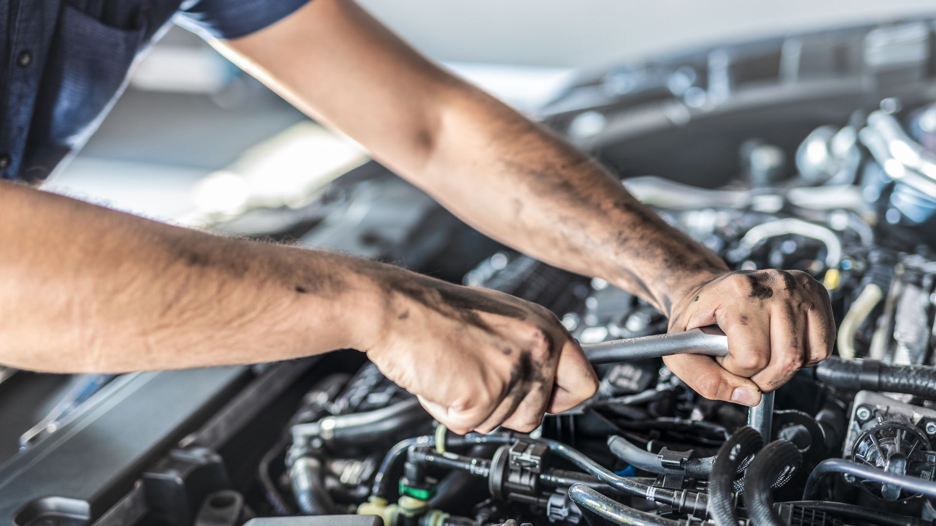 A man working on a car engine with a wrench